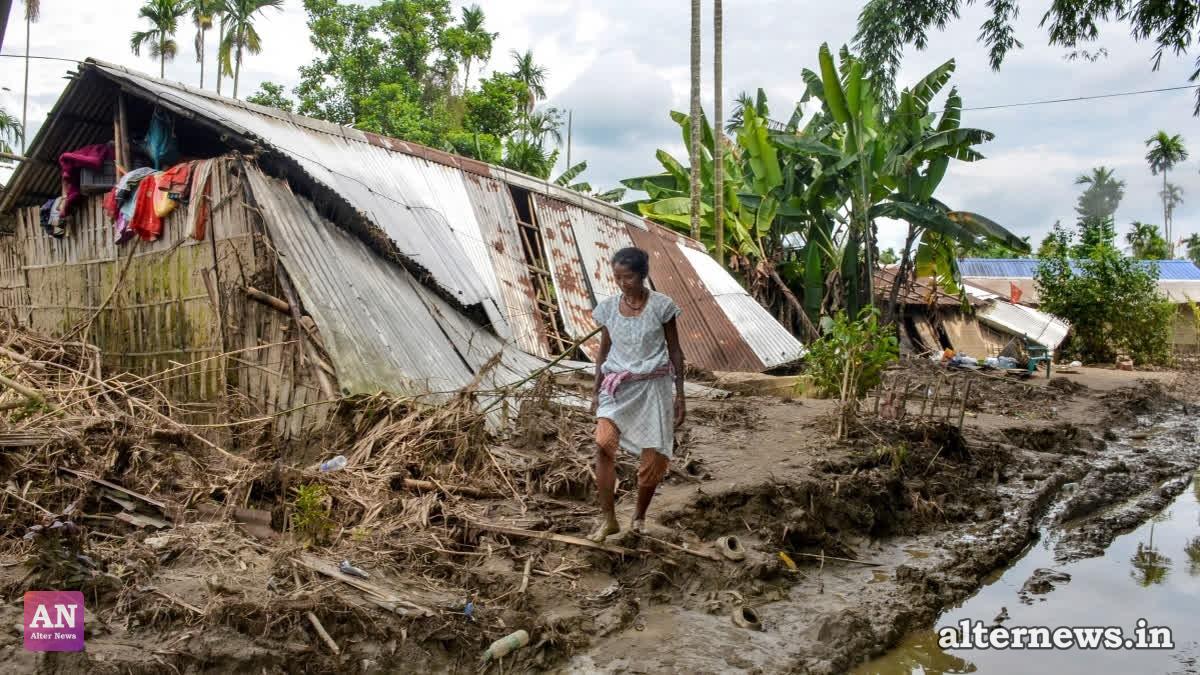 A flood-affected woman walks past a damaged house amid mud and debris, in Sivasagar district, Assam, Tuesday, Aug. 5, 2026 (PTI)