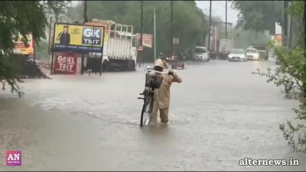 A man, carrying his bicycle, wades through knee-deep water